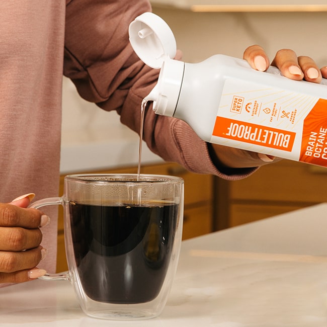 Woman pouring Bulletproof Brain Octane c8 MCT oil into glass coffee mug