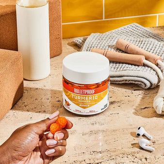 Bulletproof Turmeric Gummies held in hands next to workout equipment