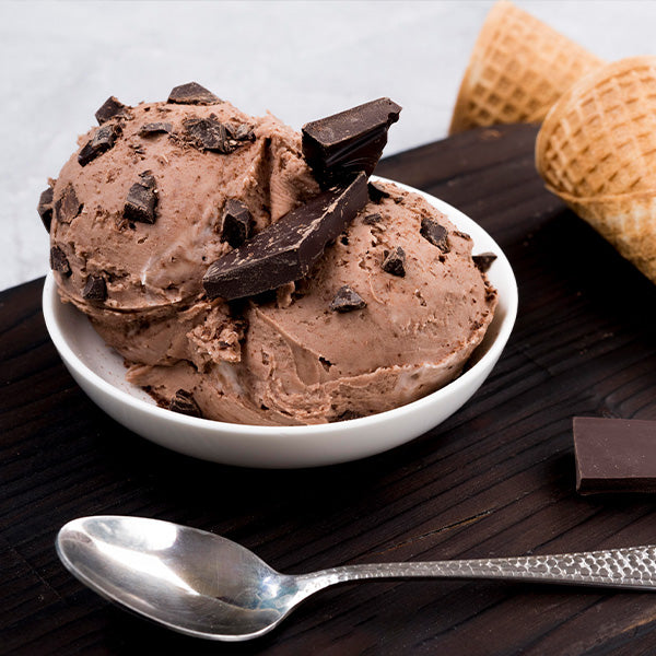 Chocolate ice cream with waffle cones and a spoon on a wooden surface