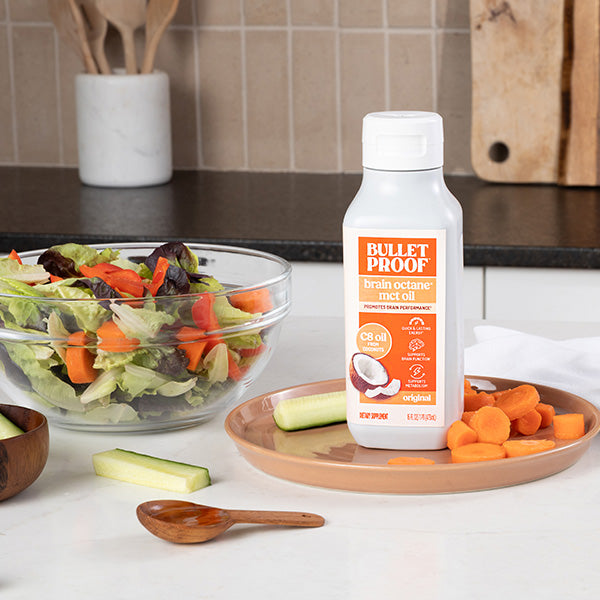 Bulletproof MCT oil on a kitchen counter with salad and vegetables