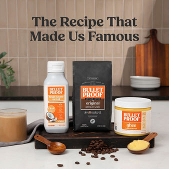 Bulletproof products including whole bean coffee, ghee, and mct oil on a kitchen counter next to coffee beans and mug of coffee