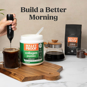 Bulletproof collagen peptides with coffee and coffee-making equipment on a marble surface.