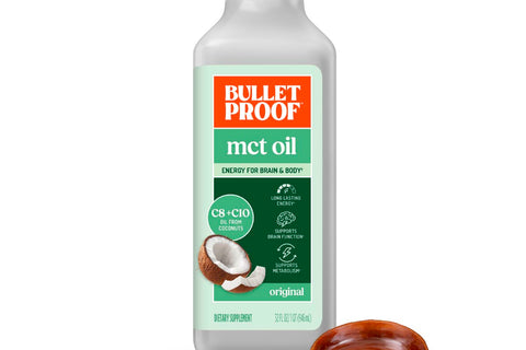 Bulletproof MCT oil bottle with a wooden scoop on a white background