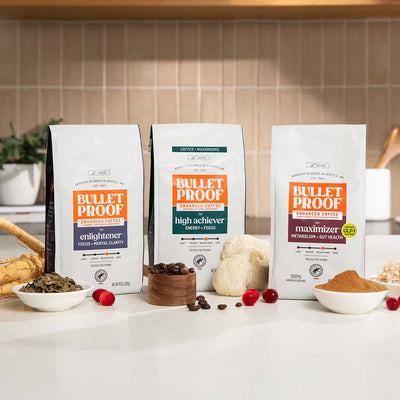 Three packages of Bulletproof functional coffee on a kitchen counter with ingredients.