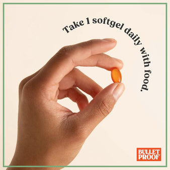 Hand holding a softgel supplement, take 1 softgel daily with food