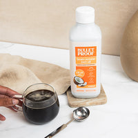 Bulletproof brain octane mct oil bottle with a glass of coffee on a marble surface.