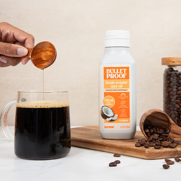 Person pouring mct oil into a mug with Bulletproof brain octane oil in the background