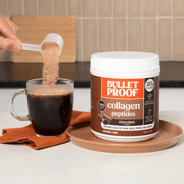 Bulletproof chocolate collagen peptides being added to a cup of coffee