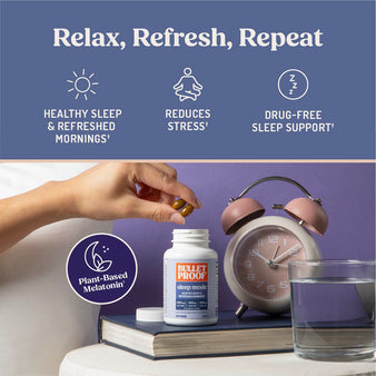 Bulletproof sleep mode bottle with a hand holding a 2 capsules, clock, and glass of water on a table.