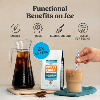 Bulletproof coffee setup with iced coffee, coffee bag, and a hand holding a straw in a glass.
