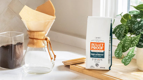 Bulletproof coffee packaging with a coffee maker and plant on a table