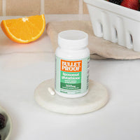 Bulletproof liposomal glutathione supplement bottle on a kitchen counter with fruit in background.