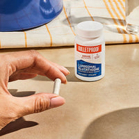 Hand holding one capsule of Bulletproof Liposomal Glutathione