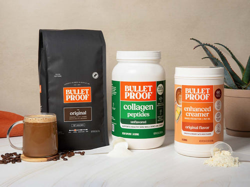 Bulletproof products including coffee, collagen peptides, and creamer on a table with a plant in the background.