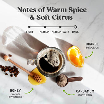 Cup of coffee next to raw honey, cardamom spices and orange slice, dark roast