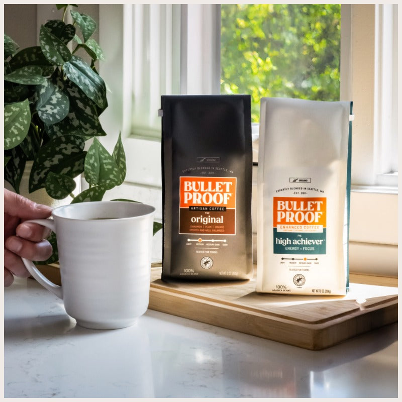 Two bags of Bulletproof coffee on windowsill next to mug of coffee